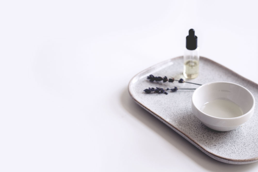 Flacon d’huile végétale et coupelle sur un plateau pour un massage prénatal