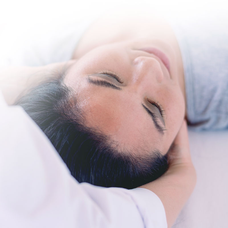 Femme allongée les yeux fermés pendant un massage tête relaxant