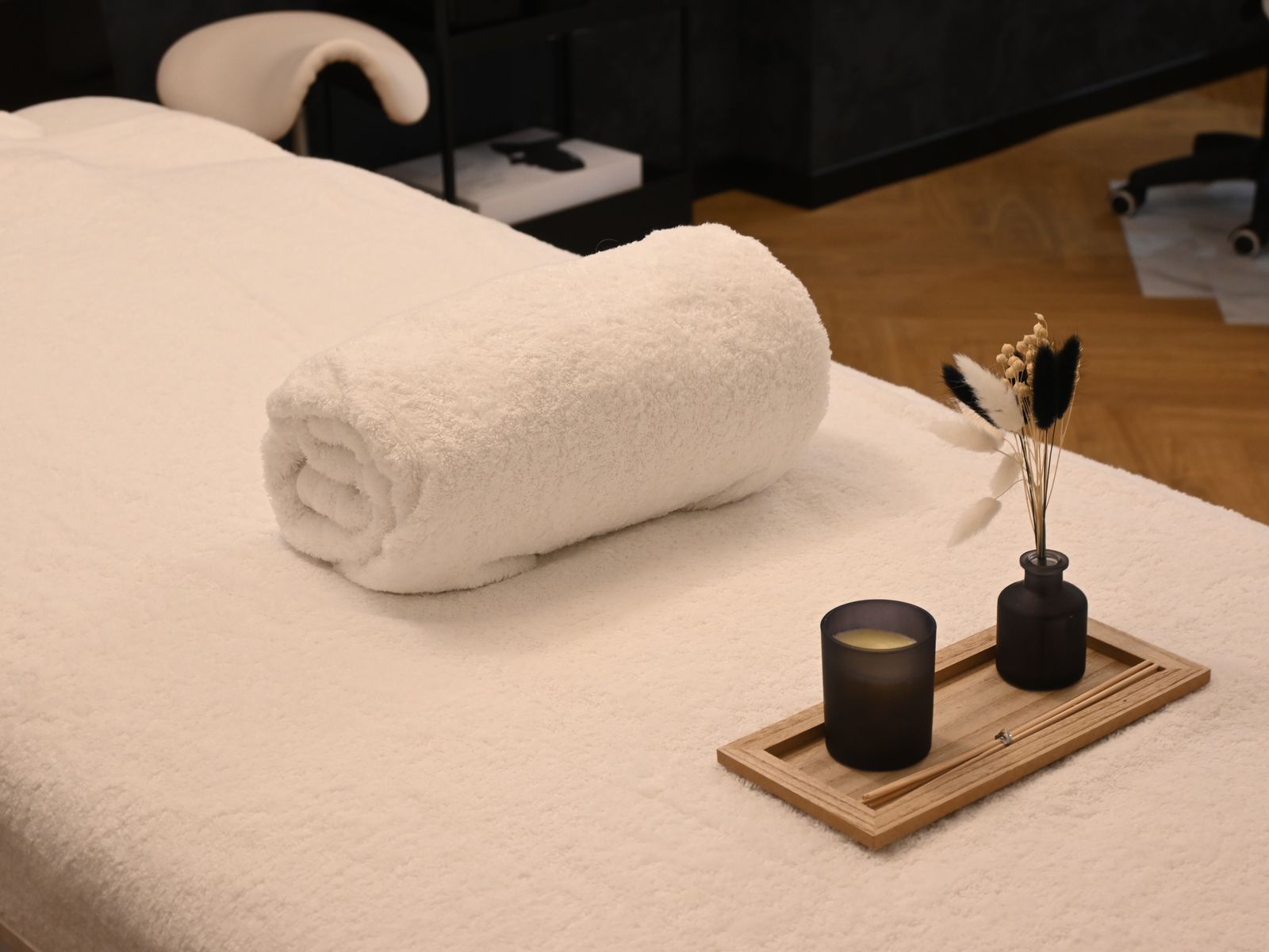 Table de massage avec serviette roulée et bougie, prête pour une séance
